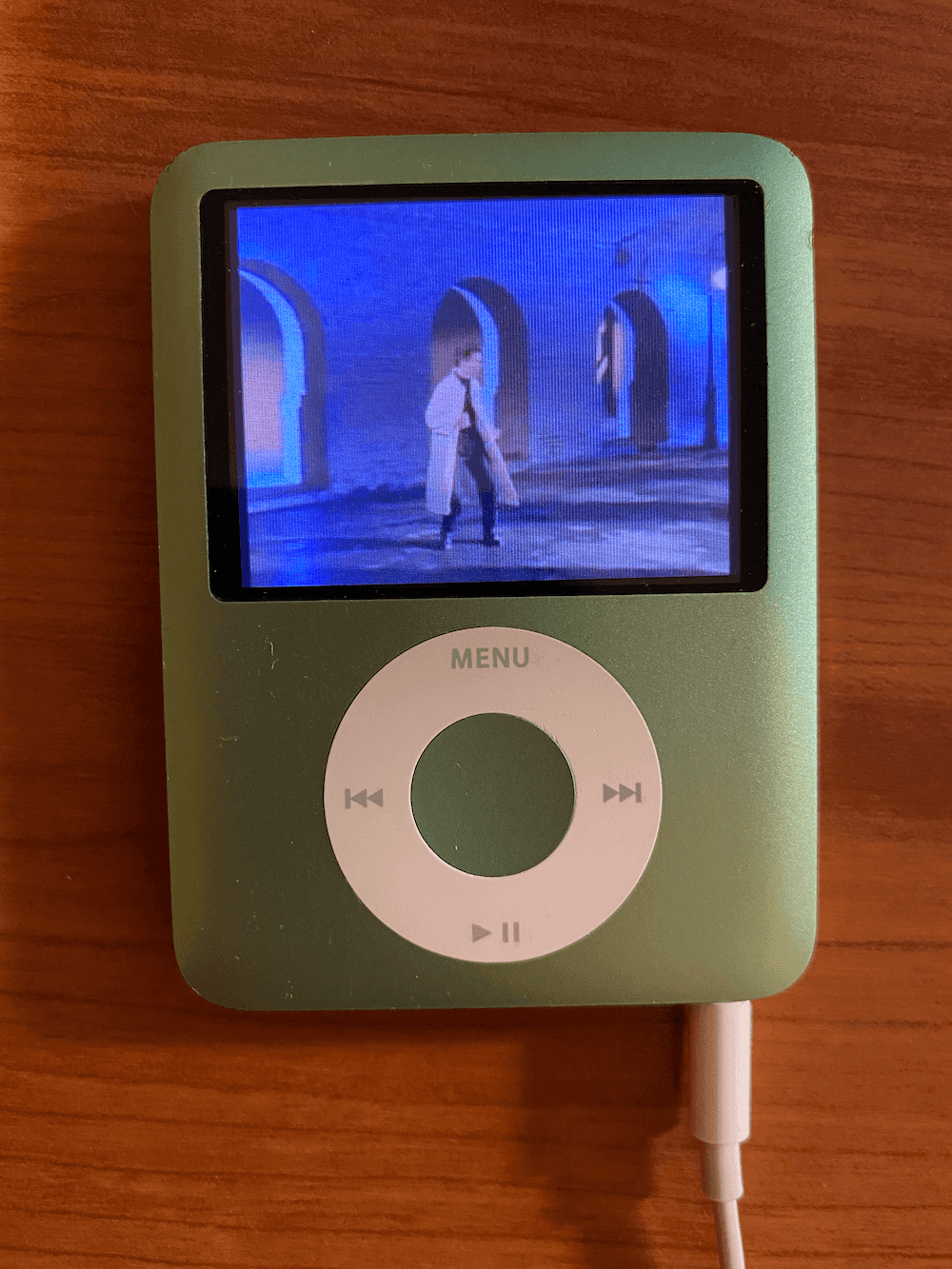 An photo of a mint green iPod nano with a video playing